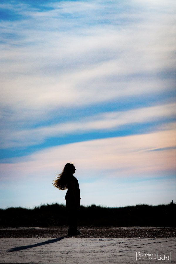 Silhouet van een vrouw op het strand bij zonsondergang