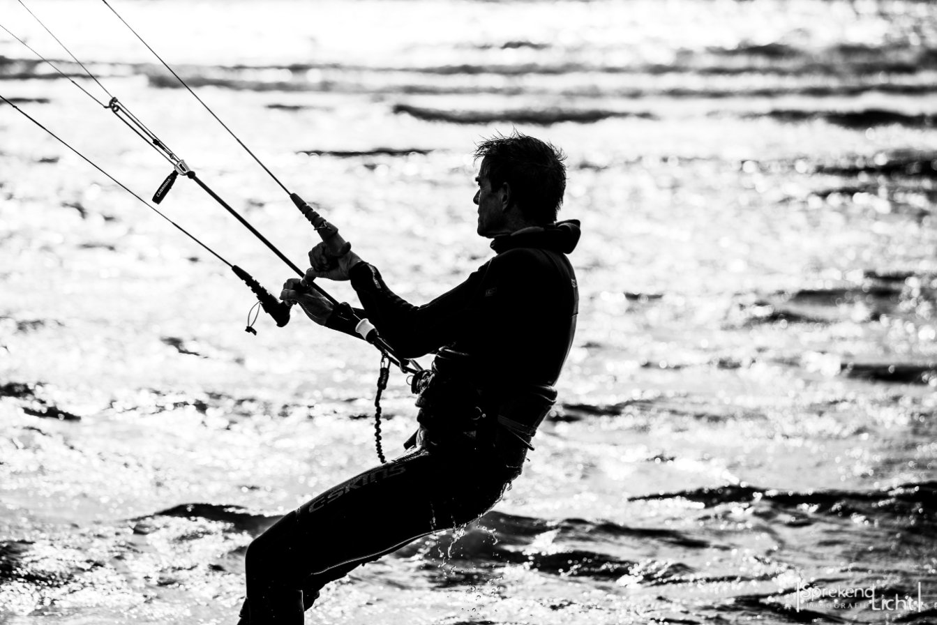Zwart-witfoto van een kitesurfer in tegenlicht